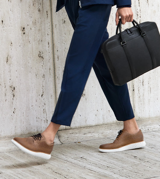 Man in tan suit laying down with feet up wearing sneakers