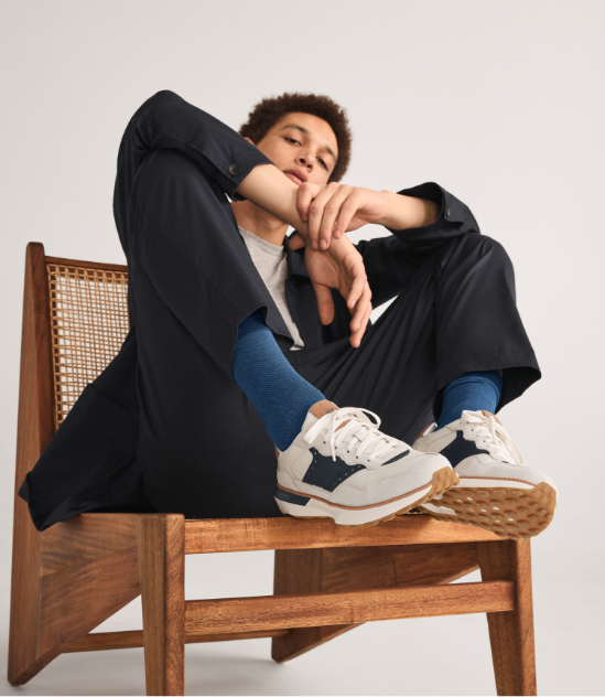 Man in tan suit laying down with feet up wearing sneakers