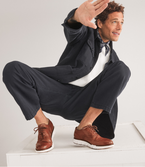 Man in tan suit laying down with feet up wearing sneakers